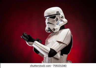 SAN BENEDETTO DEL TRONTO, ITALY. NOVEMBER 11, 2017. Studio portrait  of stormtrooper costume replica, with blaster E-11 gun. He is a fictional character of Star Wars saga. Red background 
