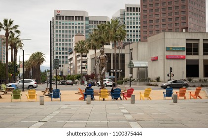 San José, California, USA - May 28, 2018: People Lounging In Adirondack Chairs At Plaza De Cesar Chavez Park, With A View Of Adobe Systems World Headquarters, In Downtown San José, Silicon Valley, CA.