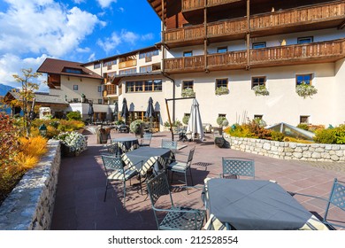 SAN CASSIANO, DOLOMITES, ITALY - SEP 25, 2013: chairs with table on sunny terrace of alpine luxury restaurant and hotel in San Cassiano village. Wealthy tourists visit northern part of Italy in autumn