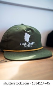 San Clemente, California / USA - September 16 2019: A Green Flat Bill Hat Resting On A Merch Shelf In Specialty Coffee Shop, Bear Coast Coffee In Southern California.