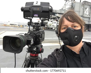 San Diego, CA / USA - May 31, 2020: Female Camera Operator Wearing Face Mask During Live Streaming Of Event On The Deck Of The USS Midway.