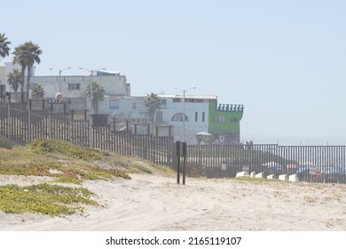 San Diego, CA, USA - May 14, 2022: Border fence between the U.S. and Mexico viewed from the beach at the Border Field State Park in San Diego, California. The city of Tijuana is seen over the fence.