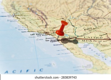 San Diego marked on map with red pushpin. Selective focus on the word San Diego and the bottom of pushpin. Pin is in an angle and casts shadow to the right. 