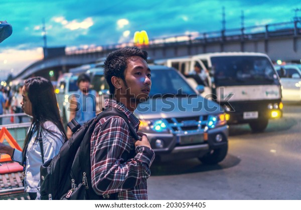 SAN FERNANDO, PHILIPPINES - Oct 07, 2016: A\
young guy waiting for a bus at the bus stop on the sidewalk in San\
Fernando, Philippines