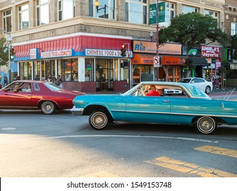 San Francisco, CA AUGUST 31, 2019: Man Rides Low Rider Car Showing Classic Rims Showing Chevrolet Flags