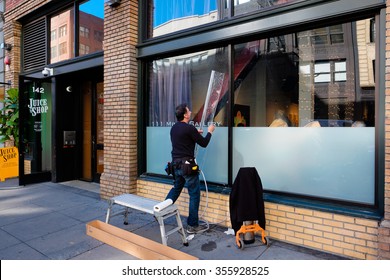 SAN FRANCISCO, CA - DECEMBER 11, 2015: Windown Decal Worker Placing A Sticker On The Window Of A Coffee Shop In San Francisco.