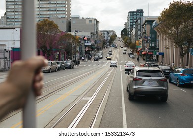 San Francisco, CA - October 6, 2019: Going Down California Street On A Cable Trolley In SF. Man's Hand Holding On The Railing Out Of Focus To The Left. 