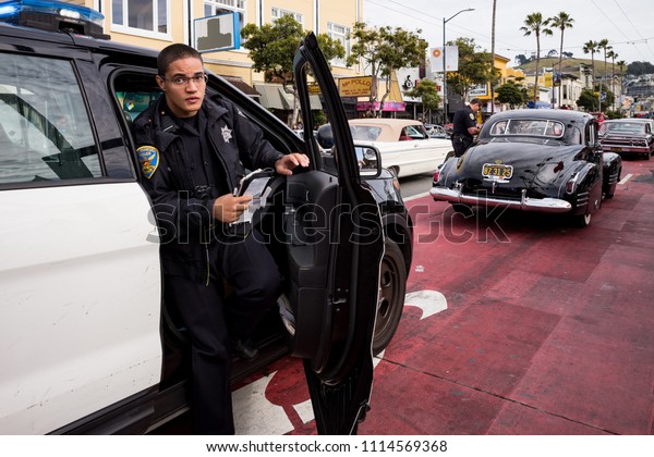 SAN\
FRANCISCO, CA, USA - MAY 5, 2018: A police officer issues a ticket\
to a lowrider in San Francisco\'s Mission\
District.