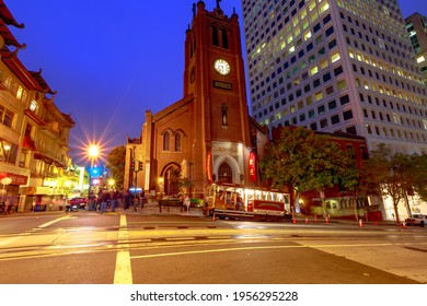San Francisco, California, United States - August 15, 2019: cable car stops in front of a historic church in San Francisco downtown by night. Light trails of cars in city Californian nightlife.