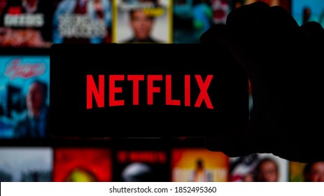 San Francisco, California, USA. 11/11/2020. Man holding a  Smartphone with the "Netflix" logo displayed, with the Netflix home page in the background. 