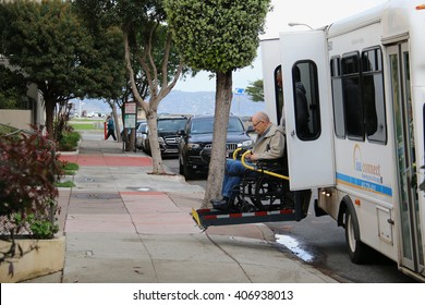 San Francisco, California, USA - December 24, 2015: Old man in a wheelchair is assisted to get off a van using a lift.