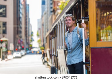 San Francisco man riding cable car tramway. Young casual guy in his 20s using public transport system in the city to travel to work or university. Summer tourism.