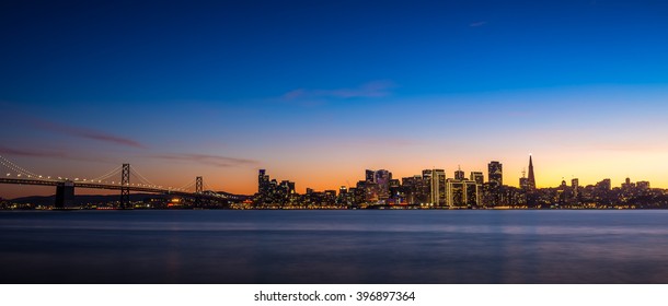 San Francisco Skyline At Dusk With City Lights And The Bay Bridge