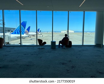 San Francisco, USA - June 27, 2022: The Silhouette Of A Man Sitting On An Airport Lounge Chair In Front Of A Window With United Airlines Airplanes In The Background