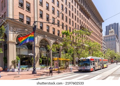 San Francisco, USA - June 6, 2022: People At Market Street Downtown In San Francisco, California With Rainbow Flag For Gay People Fluttering At An Old Historic Lantern.