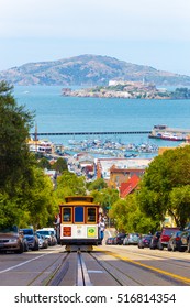 San Francisco, USA - May 19, 2016: Approaching cable car full of tourists coming uphill with Angel and Alcatraz Island, bay water in background on Hyde Street in sunny California