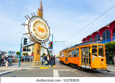 San Francisco, USA - May 5, 2016: Orange Vintage Swiss F Market Streetcar Rolls By Large Sign At Entrance To Tourist Attraction Of Fisherman's Wharf On The Corner Of Beach And Jones Street. Horizontal