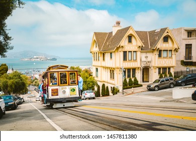 SAN FRANCISCO, USA - SEPTEMBER 3, 2016: Powell-Hyde cable car climbing up steep hill in central San Francisco with famous Alcatraz Island in the background on a sunny day with blue sky, USA.