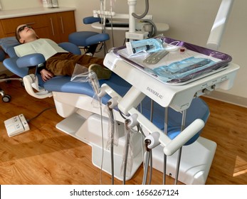 San Jose, CA - February 20, 2020: Medical equipment tray inside dental office with boy on the chair watching TV on the ceiling. 