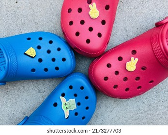 San Jose, CA - June 24, 2022: Pair Of Red And Blue Kids Foam Crocs With Jibbitz On Grey Background.