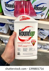 San Jose, CA - May 15, 2019: Man Holding Up A Bottle Of Round Up Weed And Grass Killer Concentrate Plus In A Home Improvement Store. Manufactured By Monsanto Corporation.