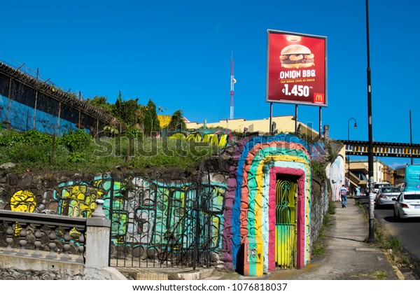 San Jose, Costa Rica. February\
2, 2018. A side walk in downtown San Jose, Costa Rica, on a busy\
afternoon with a rainbow-painted doorway and McDonalds\
ad