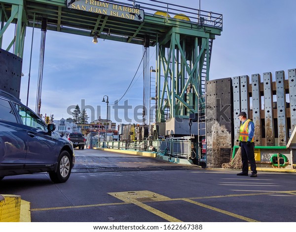 San Juan Island, WA / USA - circa\
November 2019: Man directing vehicle traffic off of a Washington\
State Ferry docked at Friday Harbor on San Juan\
Island.