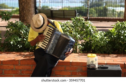 SAN JUAN, PUERTO RICO - January 7, 2015: Ancient Playing Accordion For Tips On Public Square Of The Capital. Representation Of Culture, Poverty And Economic Crisis.