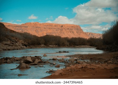 San Juan River flowing near Bluff Utah, desert wash pushing boulders into the river with large fluffy clouds blanketing the sky - Powered by Shutterstock