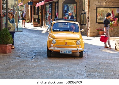 San Marino, Italy - August 22, 2015: Old Yellow Car Fiat 500 In The Street With People In San Marino