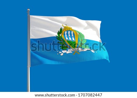 San Marino national flag waving in the wind on a deep blue sky. High quality fabric. International relations concept.