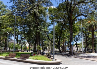 San Miguel de Tucuman, Tucuman, Argentina. 02-12-2022: City square with tall trees, sun and few people walking around.