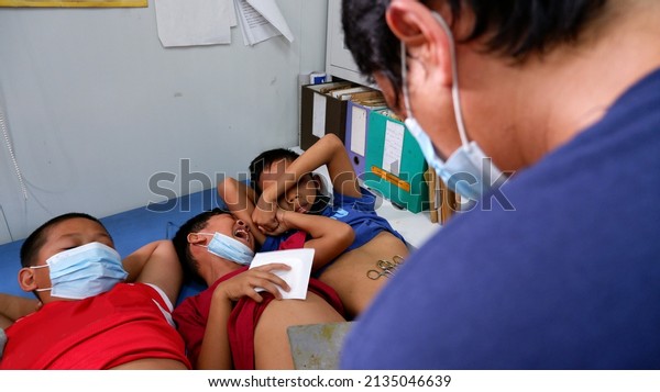 San Pablo City, Laguna, Philippines - March\
11, 2022: Boy cries in pain for being circumcised a male paramedic\
volunteer in a free medical service organized and funded by a\
fraternity organization