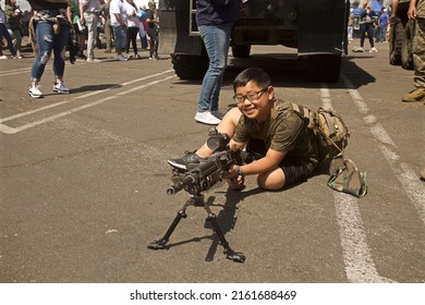 San Pedro, California: 
May 28, 2022: 
A Young Boy Aims An Automatic Assault Rifle During An LA Fleet Week Demonstration Four Days After The Elementary School Mass Shooting In Uvalde, Texas.