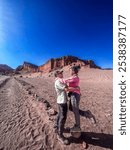 San Pedro de Atacama, Antofagasta Region, Chile - September 20, 2024: Couple in the Valley of the Moon, Atacama Desert, in the background you can see a rock formation called the Amphitheater.