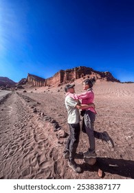 San Pedro de Atacama, Antofagasta Region, Chile - September 20, 2024: Couple in the Valley of the Moon, Atacama Desert, in the background you can see a rock formation called the Amphitheater.