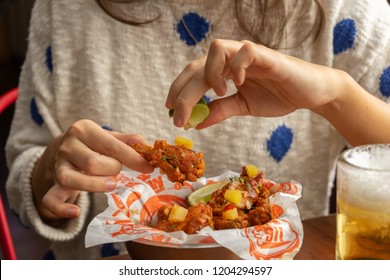 SAN SALVADOR, EL SALVADOR, CENTRO AMERICA - OCTOBER 15, 2018 Person Eating Buffalo Wings With Hands Full Of Sauce At Buffalo Wings Restaurant, El Salvador, Central America.