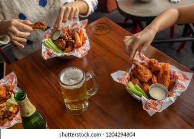 SAN SALVADOR, EL SALVADOR, CENTRO AMERICA - OCTOBER 15, 2018 Person Eating Buffalo Wings With Hands Full Of Sauce At Buffalo Wings Restaurant, El Salvador, Central America.