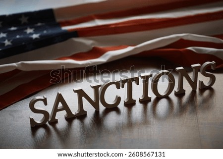 Sanctions Concept with American Flag and Wooden Letters on Table