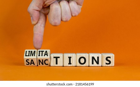 Sanctions Or Limitations Symbol. Businessman Turns Cubes, Changes The Word Sanctions To Limitations. Beautiful Orange Table, Orange Background, Copy Space. Business, Sanction Or Limitation Concept.