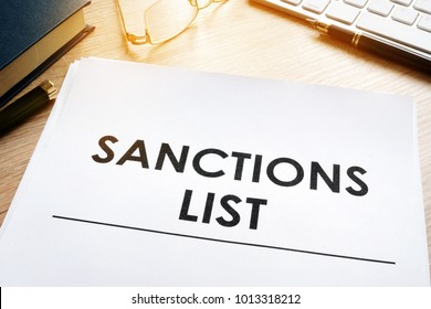 Sanctions List On A Desk. Keyboard, Glasses And Book. Government Act For Sanctioned Countries Concept.