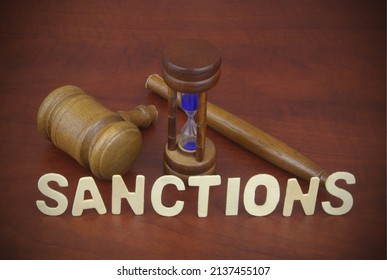 Sanctions time concept. Word  sanctions and broken judge gavel with hourglass.