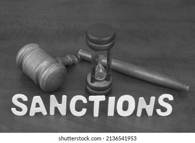 Sanctions time. Letters sanctions and broken judge gavel with hourglass.	