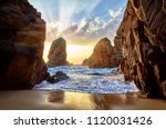 Sand beach among rocks on evening sunset. Ursa Beach near Cape Roca (Cabo da Roca) at Atlantic Ocean coast in Portugal. Summer landscape.