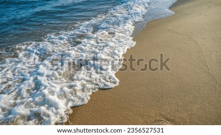 Sand beach and blue sea. Close up soft wave lapped the sandy beach. Beautiful sea waves with foam of blue and turquoise color isolated. Powerful ocean blue waves.