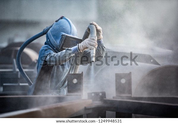 Sand blasting process, Industial worker using\
sand blasting process preparation cleaning surface on steel before\
painting in factory\
workshop.