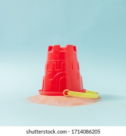 Sand Castle Bucket With Spilled Sand Against Pastel Blue Background. Minimal Summer Vacation Concept.