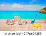 Sand castle and child toys on sand beach at tropical resort. Family vacation. Relax on the beautiful sea coast beach. Azure water on the ocean, sea coast resort. Summer holidays. Blue sky. Copy space.