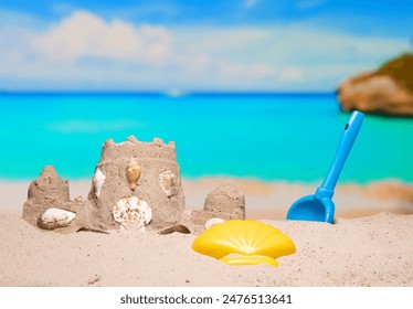 Sand castle and child toys on sand beach at tropical resort. Family vacation. Relax on the beautiful sea coast beach. Azure water on the ocean, sea coast resort. Summer holidays. Blue sky. Copy space. - Powered by Shutterstock