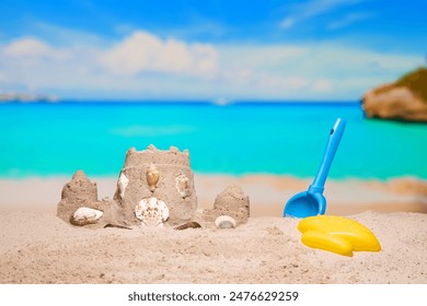 Sand castle and child toys on sand beach at tropical resort. Family vacation. Relax on the beautiful sea coast beach. Azure water on the ocean, sea coast resort. Summer holidays. Blue sky. Copy space. - Powered by Shutterstock